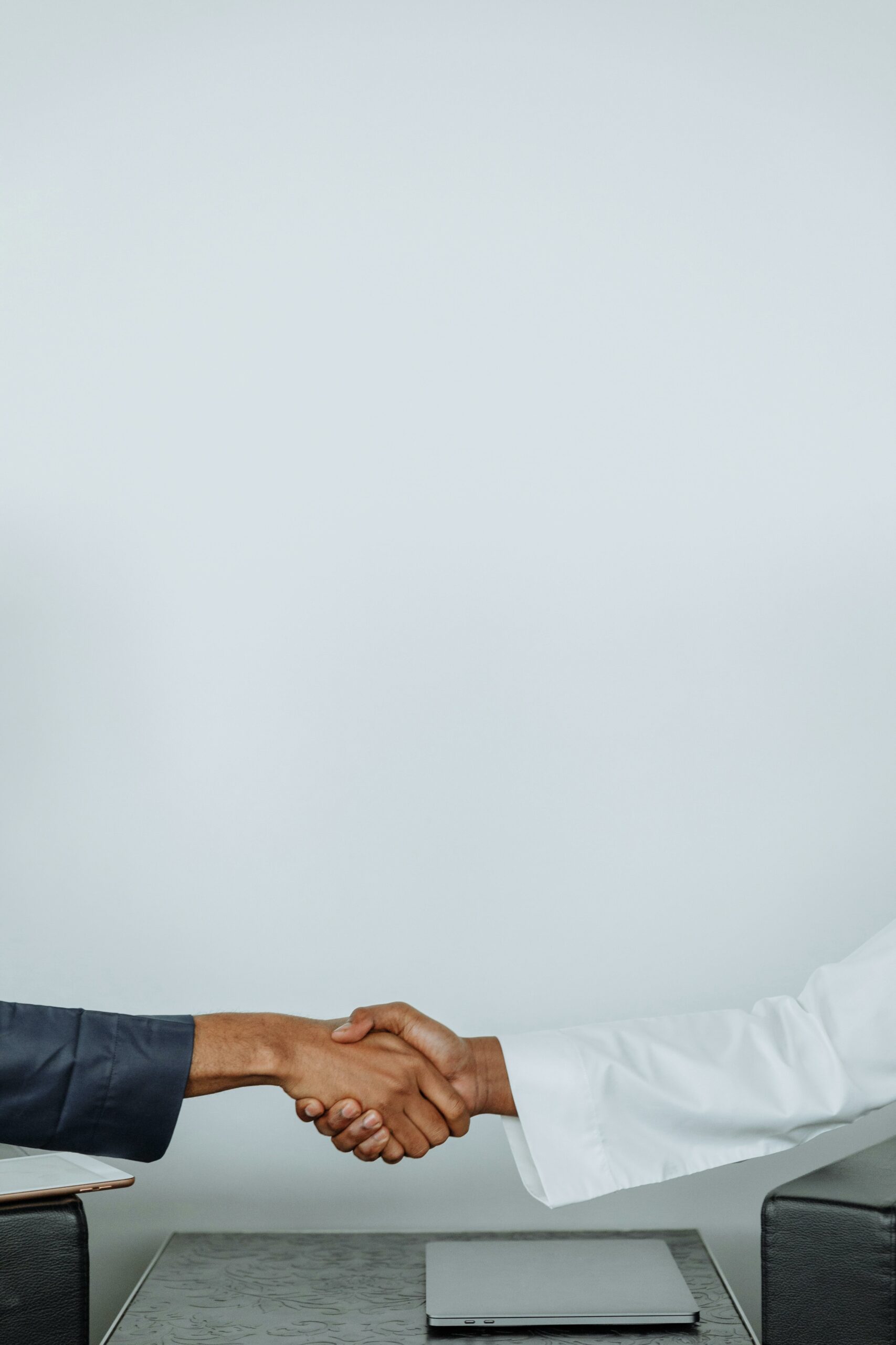 Close-up of two diverse professionals shaking hands across a table indoors.