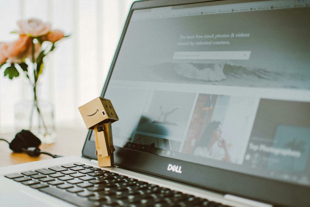 pexels photo 2363482 2363482 A small toy figure stands on a laptop keyboard with flowers in the background.