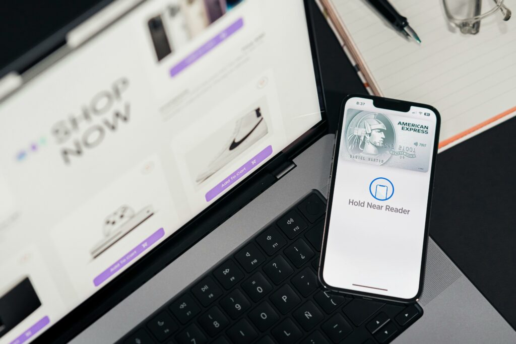 pexels photo 29502378 29502378 Smartphone with payment terminal app next to laptop displaying online shopping site.