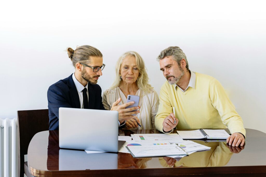 pexels photo 5816286 5816286 Three individuals collaborating on financial documents during a business meeting.